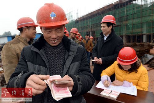  资料图片：2014年1月11日，农民工钟弼桂（左二）在江西省高安市工业园区的一个建筑工地上点数领到的工资。