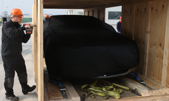 木箱内的车辆经由地面固定，并罩有保护的车衣