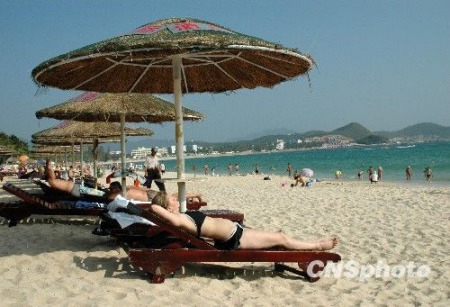 图为游客在海南三亚海滩享受阳光沙滩。 (中新社发 尹海明 摄)