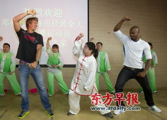 　　昨天上午，牙买加飞人鲍威尔(前排右)来到徐汇阳光之家，陪智障孩子一起做游戏。早报见习记者 管开吉 图