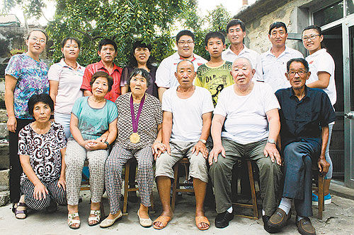  8月19日，山东省烟台市牟平区大窑镇西吕村，全村的父老乡亲到村口迎回了奥运举重冠军周璐璐。一到家，璐璐就为奶奶挂上金牌。父亲说这是璐璐三年来第一次回家，全家终于盼来了家庭成员最齐的一张全家福。郭鑫摄