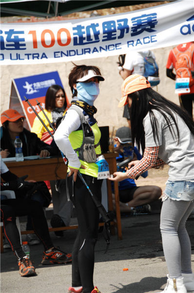 志愿者正在给一位参加百公里的女选手扫码计时。摄影：于峰