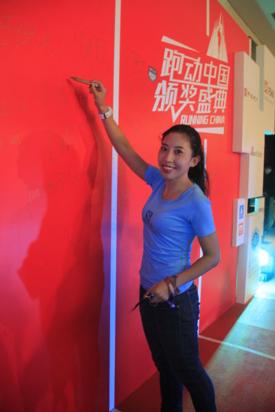 图为知名越野跑者珊瑚在签字墙前拍照留念。